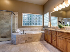Large bathroom with wood cabinets and marble floor and tub.