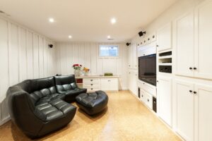 Finished basement of a residential home with an entertainment center, couch, and television